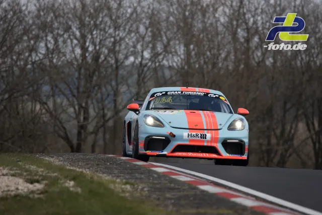 Porsche 718 Cayman GT4 in hellblau-oranger Lackierung auf Kuppe der Nürburgring-Nordschleife während des NLS-Rennens