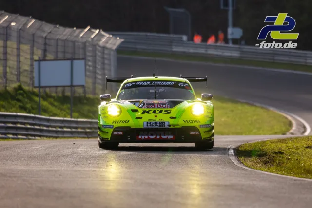 Neongelber Porsche 911 GT3 R mit eingeschalteten Scheinwerfern auf der Nürburgring-Nordschleife während des Zeittrainings.