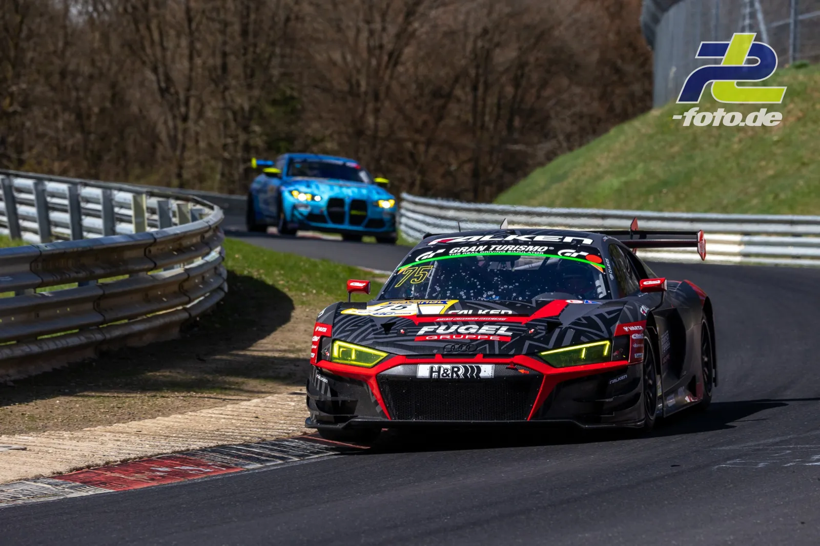 Zwei Rennwagen in einer Kurve auf dem Nürburgring, vorn ein Audi R8 LMS in schwarz-rot-gelb, dahinter ein blauer BMW M4 GT3.