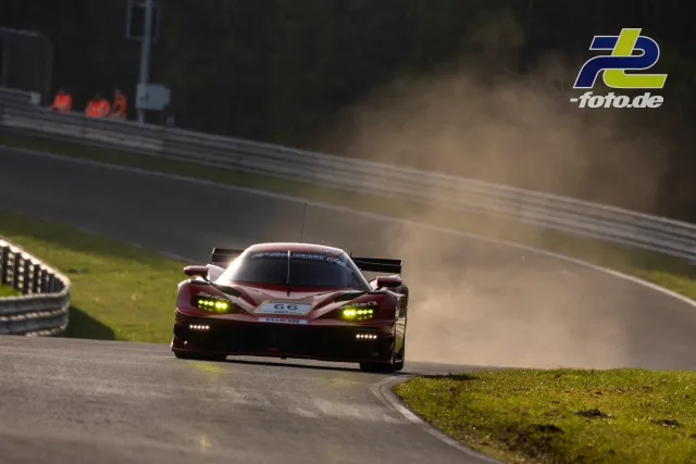 Dunkelroter Rennwagen Nr. 66 mit weißem Dach in Kurve auf dem Nürburgring beim Zeittraining, Staubwolke im Hintergrund.