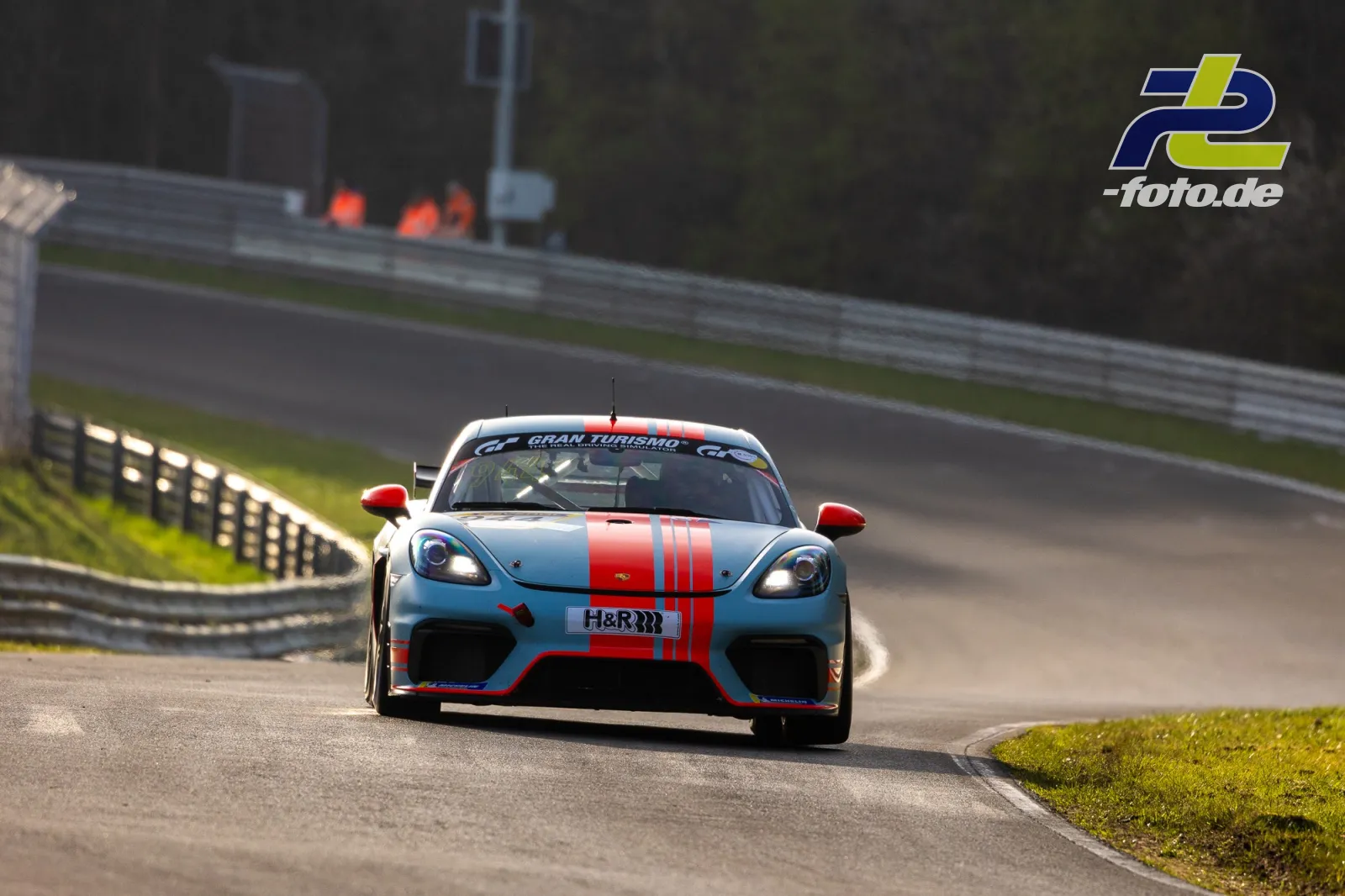 Porsche 718 Cayman GT4 CS in hellblauer Lackierung mit rotem Mittelstreifen auf der Nürburgring-Nordschleife im Zeittraining.