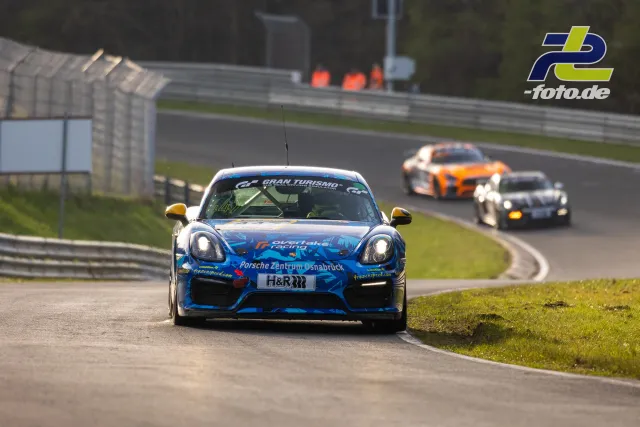 Blauer Porsche Cayman GT4 CS vom Porsche Zentrum Osnabrück auf der Nordschleife des Nürburgrings, gefolgt von zwei weiteren Rennfahrzeugen.