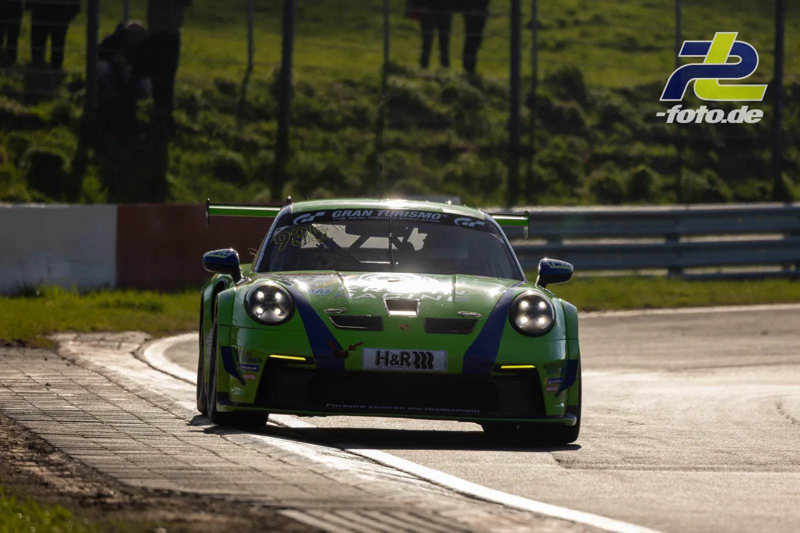Grüner Porsche 911 GT3 R #935 mit H&R-Sponsoring im Zeittraining auf dem Nürburgring beim Anbremsen einer Kurve.