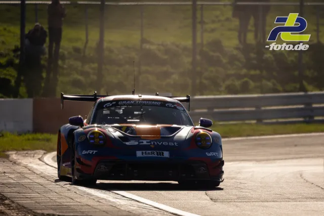 Porsche 911 GT3 R in dunkelblau-orange-weißer Lackierung beim Zeittraining auf dem Nürburgring, Frontalansicht auf der Strecke.