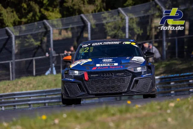 Audi Rennwagen #821 in Blau-Schwarz auf der Nürburgring Nordschleife beim NLS-Rennen, Frontalansicht in einer Kurve.