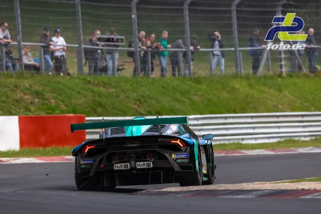 Lamborghini GT3-Rennwagen auf der Nordschleife des Nürburgrings, Zuschauer beobachten das Rennen vom Zaun aus.