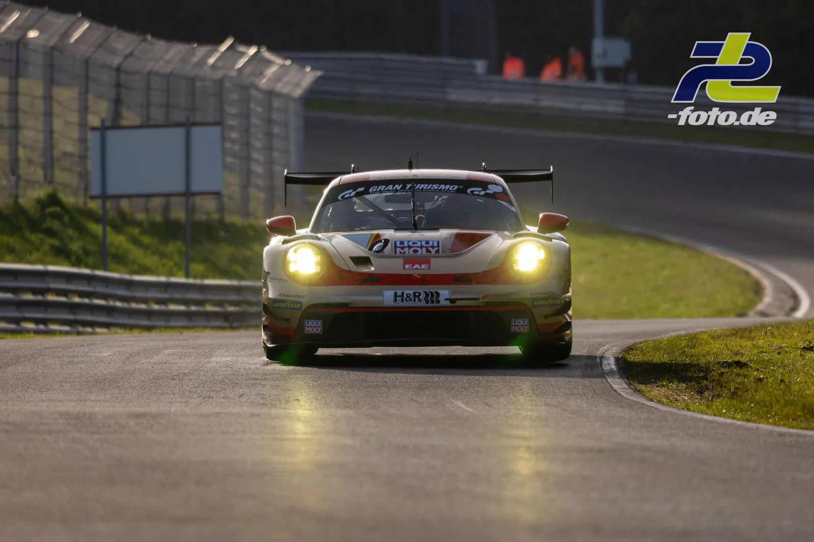 GT3-Rennwagen mit Frontalansicht in Kurve auf der Nürburgring-Nordschleife, eingeschaltete Scheinwerfer