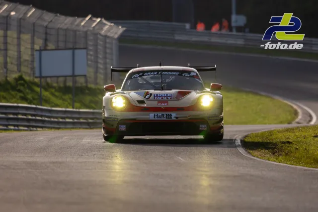 GT3-Rennwagen mit Frontalansicht in Kurve auf der Nürburgring-Nordschleife, eingeschaltete Scheinwerfer