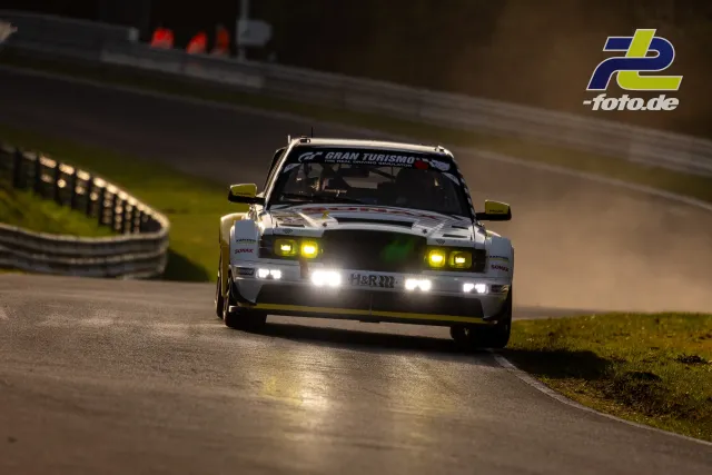 Weißer HWA EVO.R mit gelben Spiegeln und eingeschalteten Scheinwerfern in Kurve auf der Nordschleife bei Dämmerung während des Zeittrainings.