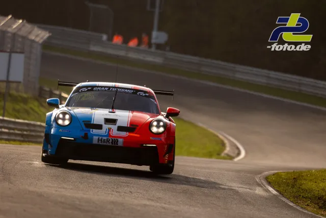 Porsche 911 GT3 R in blau-weißer-roter Lackierung in Kurve auf der Nürburgring Nordschleife beim Zeittraining