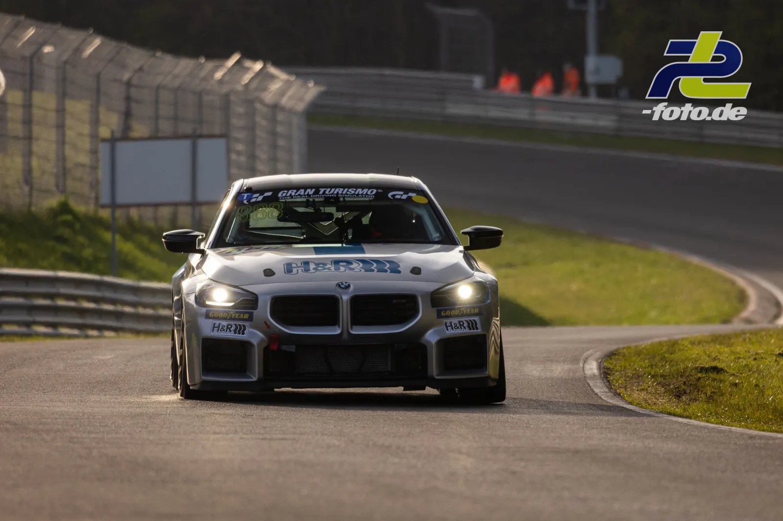 BMW im Zeittraining auf dem Nürburgring während des NLS-Laufs, Frontansicht mit eingeschalteten Scheinwerfern.