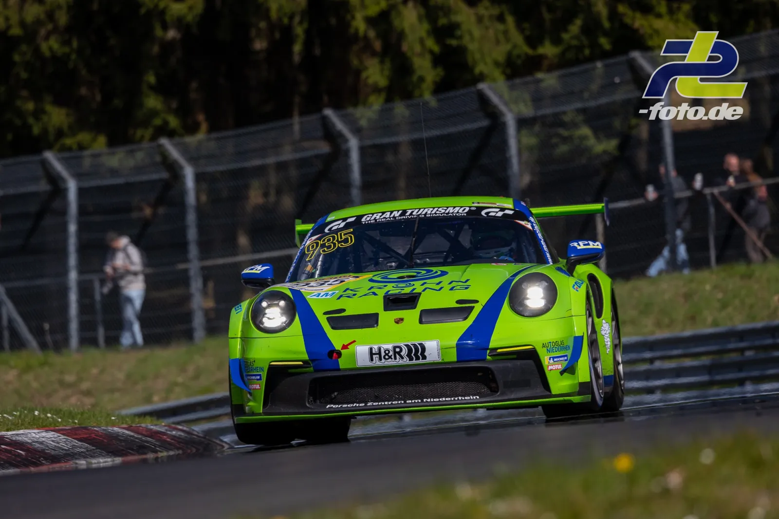Porsche 911 GT3 R in leuchtend grüner Lackierung mit Startnummer 935 auf der Nordschleife des Nürburgrings während des Rennens.