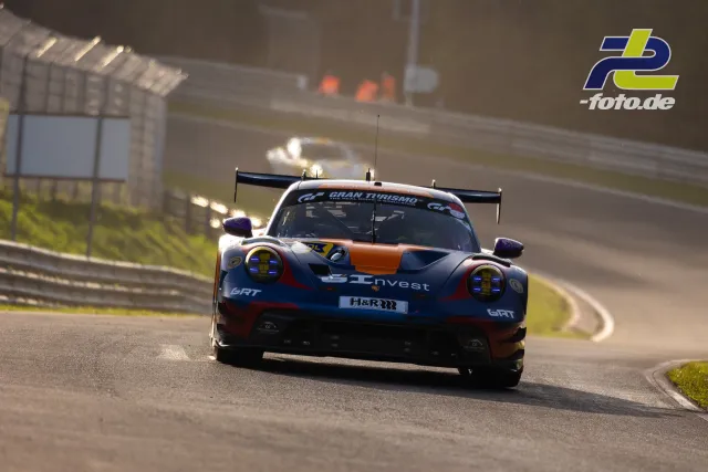 Porsche 911 GT3 R in dunkelblau-oranger Lackierung in Kurve auf der Nordschleife des Nürburgrings während des Zeittrainings.
