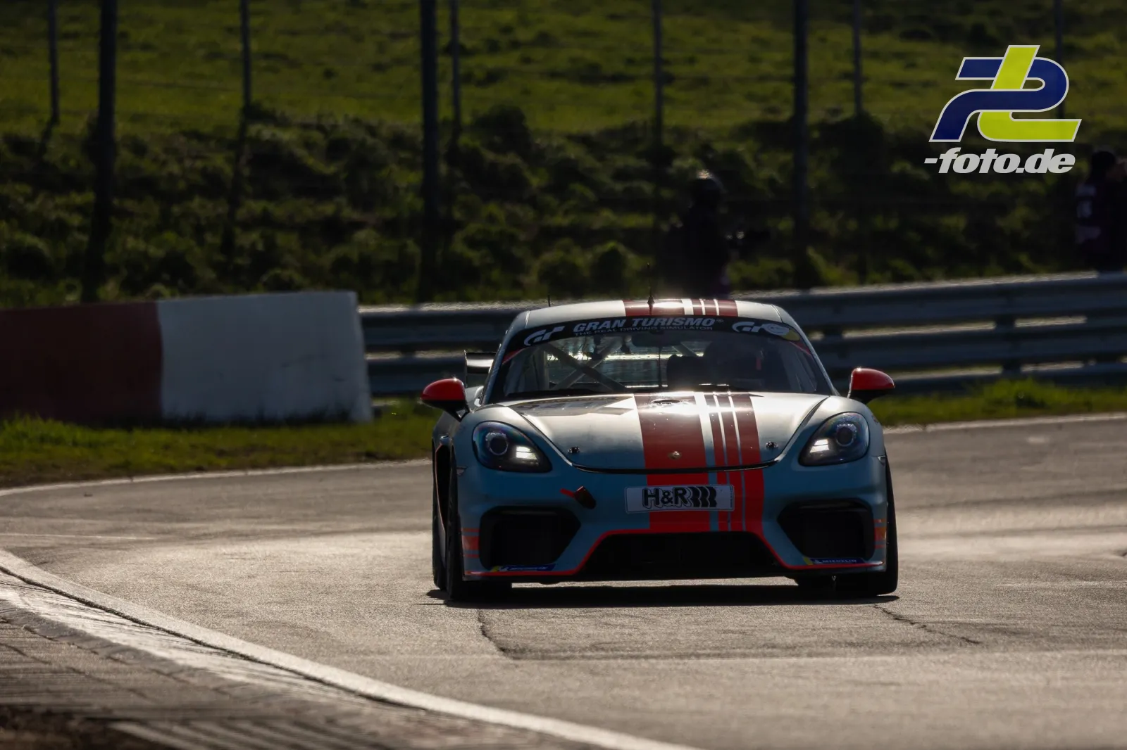 Porsche 718 Cayman in hellblau-roter Lackierung mit weißen Streifen während des Zeittrainings auf dem Nürburgring