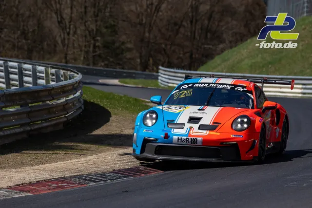 Porsche 911 GT3 R in auffälliger blau-orange-weißer Lackierung in Kurve auf der Nordschleife bei NLS-Lauf.