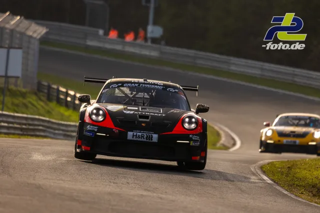 Porsche 911 GT3 in schwarz-rot bei Trainingsfahrt auf dem Nürburgring Nordschleife, gefolgt von einem weiteren Rennwagen.