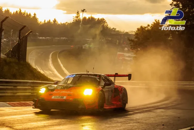 Porsche 911 GT3 R bei untergehender Sonne auf nasser Strecke mit Gischt auf dem Nürburgring während des Qualifyings.