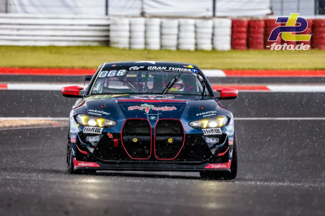 BMW M4 GT4 Nummer 180 mit dunkelblauen Rennlackierung und roten Akzenten auf nasser Strecke bei Regen am Nürburgring.