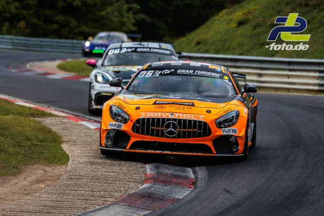 Oranger Mercedes-AMG GT vor zwei weiteren Fahrzeugen in einer Kurve während des 24h-Rennens auf dem Nürburgring
