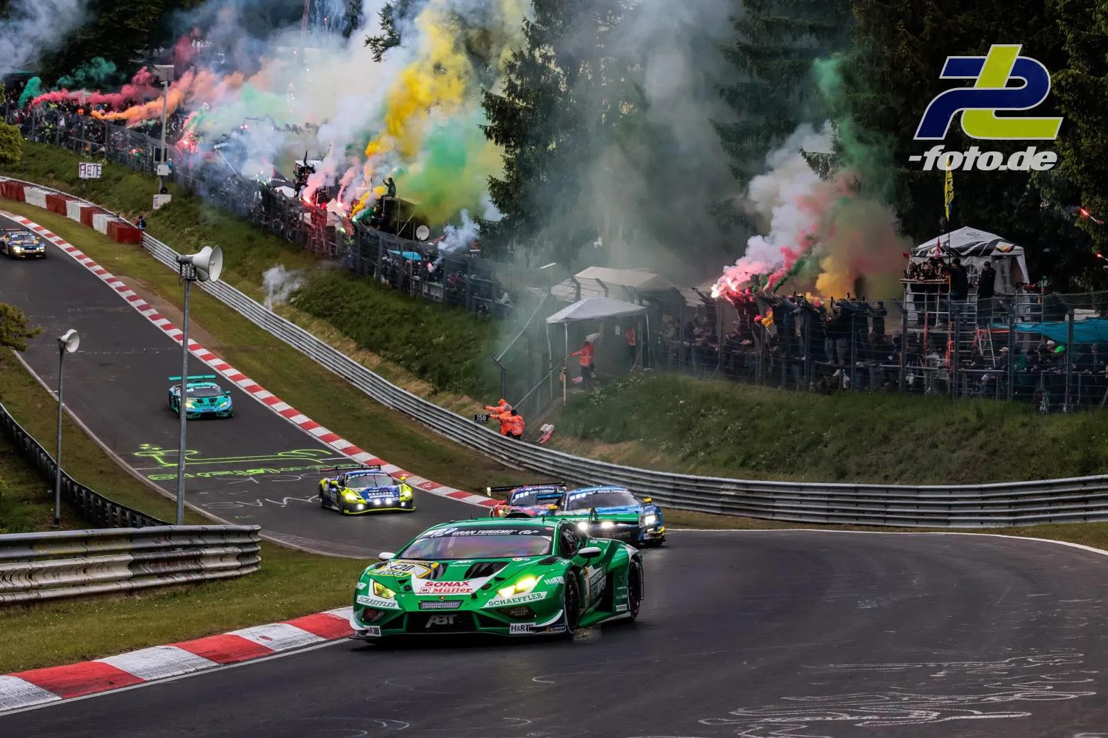 Lamborghini Huracan GT3 EVO2 des Red Bull Team ABT in der Formationsrunde auf der Nordschleife, Zuschauer mit bunten Rauchfackeln am Streckenrand.