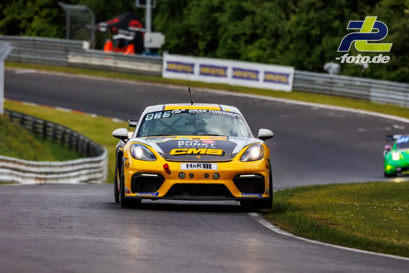 Porsche 718 Cayman GT4 Clubsport #962 in Kurve auf der Nordschleife beim 24h-Rennen Nürburgring Qualifying, gelb-schwarze Lackierung.