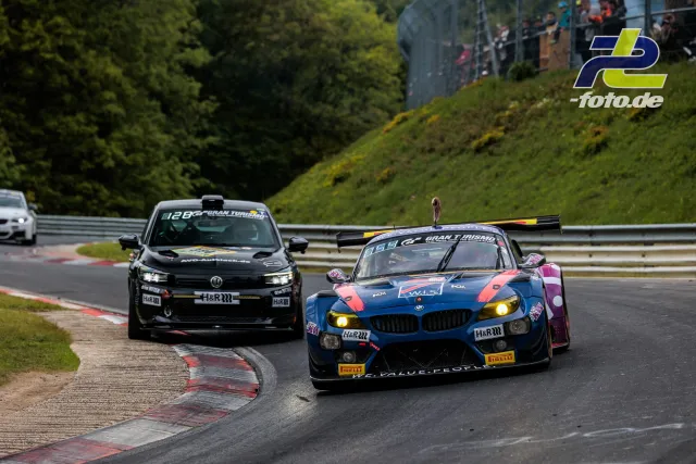 BMW Z4 GT3 und VW Golf GTI im Rennen auf der Nürburgring-Nordschleife bei Tageslicht, Zuschauer im Hintergrund