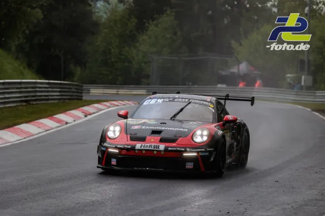 Porsche 911 GT3 R #900 in rot-schwarzer Lackierung auf nasser Strecke beim Qualifying am Nürburgring, weiteres Fahrzeug im Hintergrund.