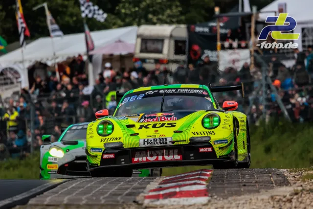Porsche 911 GT3 R in neongelber ROWE-Lackierung beim 24h-Rennen Nürburgring, gefolgt von grünem Porsche, Zuschauerzelte im Hintergrund