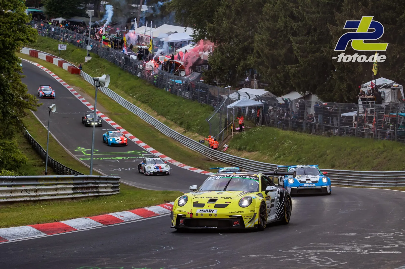 Mehrere GT3-Fahrzeuge in der Formationsrunde auf der Nordschleife mit Zuschauern und Rauchfahnen im Hintergrund