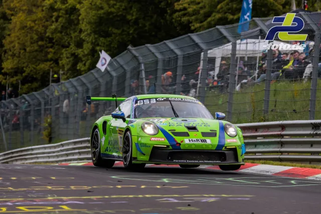 Grüner Porsche 911 GT3 R mit Startnummer 777 auf der Nürburgring-Nordschleife, im Hintergrund Zuschauer und Fangtore.