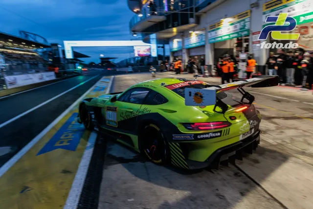 Grüner Mercedes-AMG GT3-Rennwagen verlässt bei Dämmerung die Boxengasse des Nürburgrings während des 24-Stunden-Rennens.
