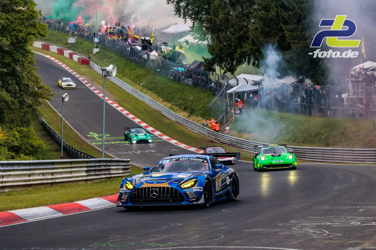 Mercedes-AMG GT3 führt Fahrzeugfeld auf nasser Nordschleife, begeisterte Zuschauer mit Rauchfackeln an der Strecke