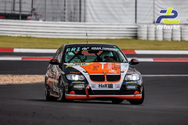 BMW 3er in schwarz-orange-weißer Lackierung während der Qualifikation auf dem Nürburgring, Frontansicht mit Curbs im Hintergrund