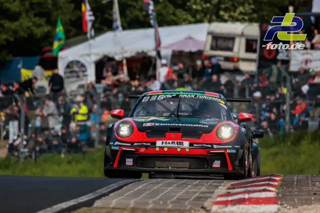 Porsche 911 GT3 R in schwarz-roter Lackierung mit H&R auf der Nordschleife, Zuschauer und Zelte im Hintergrund