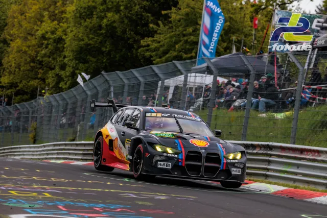 BMW M4 GT3 in schwarz-roter Shell-Lackierung in Kurve auf der Nürburgring-Nordschleife während des 24-Stunden-Rennens.