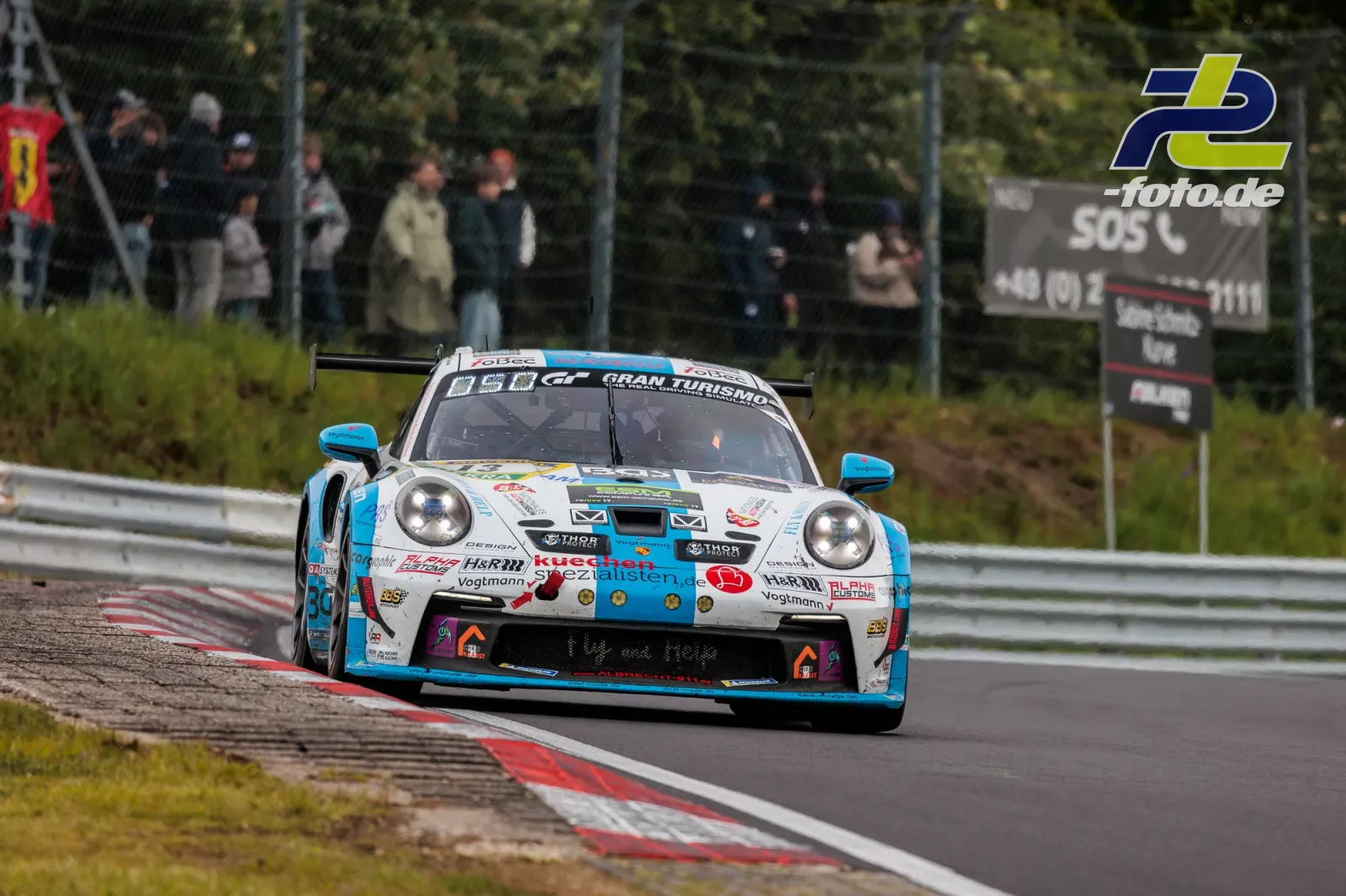 Porsche 911 GT3 Cup in weiß-blau während des 24h-Rennens auf dem Nürburgring, Zuschauer im Hintergrund