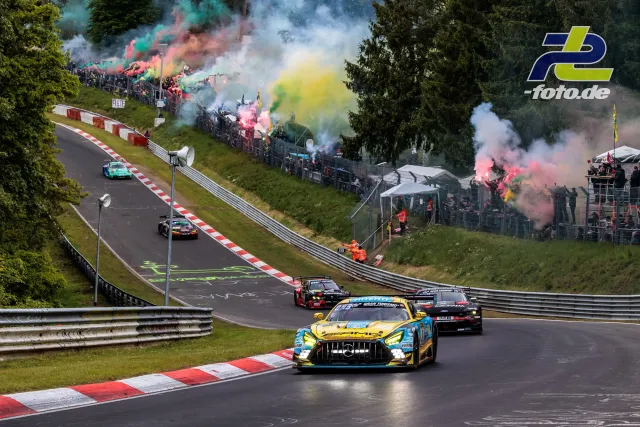 Rennfahrzeuge durchfahren Kurve auf dem Nürburgring während Formationsrunde, Zuschauer mit buntem Rauch an der Strecke