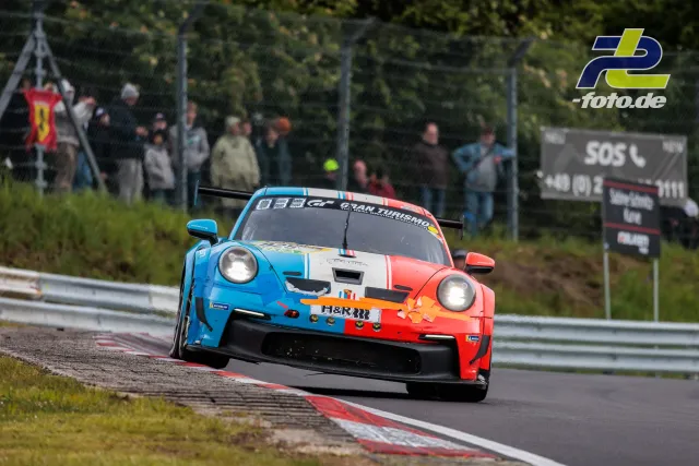 Porsche 911 GT3 R mit auffälliger blau-weiß-roter Lackierung in Kurve auf der Nordschleife während des 24h-Rennens