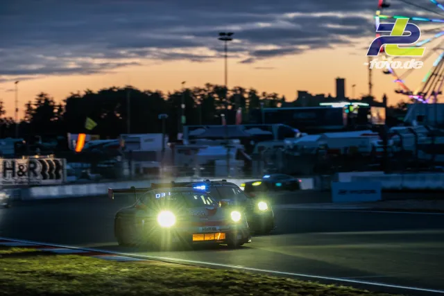 Porsche 911 mit Startnummer 5 in der Abenddämmerung auf dem Nürburgring beim 24-Stunden-Rennen mit eingeschalteten Scheinwerfern.