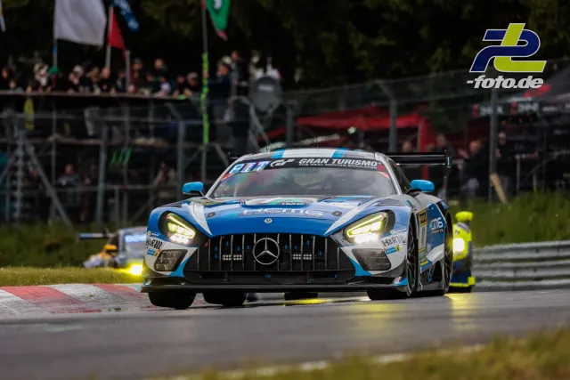Mercedes-AMG GT3 fährt bei feuchten Bedingungen auf dem Nürburgring, Zuschauer im Hintergrund.