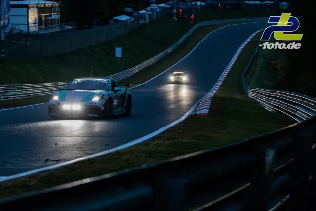 Porsche mit weißer und türkiser Lackierung bei Nachtfahrt auf dem Nürburgring, gefolgt von einem weiteren Fahrzeug.