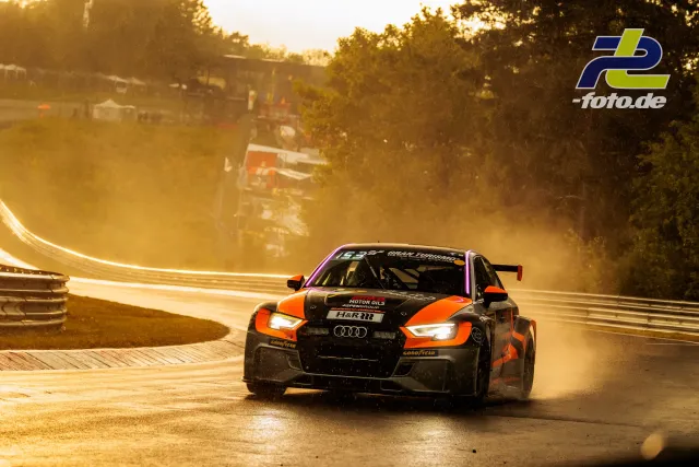 Audi TCR #821 auf nasser Nordschleife im Gegenlicht bei Qualifying zum 24h-Rennen. Gischt und goldenes Abendlicht schaffen dramatische Stimmung.