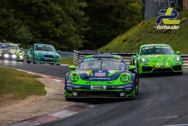 Porsche 911 GT3 R in neongrün-schwarzer Lackierung führt das Feld auf der Nürburgring-Nordschleife an, gefolgt von weiteren Rennfahrzeugen.