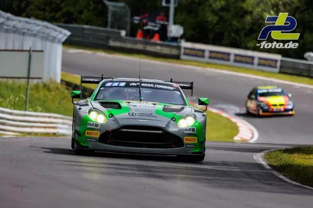Aston Martin Vantage GT3 in grün-grauer Lackierung auf der Nordschleife, gefolgt von buntem Porsche während Qualifying.