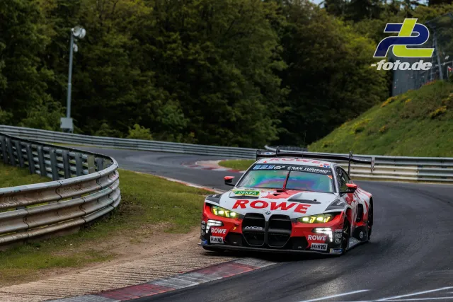 BMW M4 GT3 in rot-weißer ROWE-Lackierung nutzt den Randstein auf dem Nürburgring während des 24-Stunden-Rennens.
