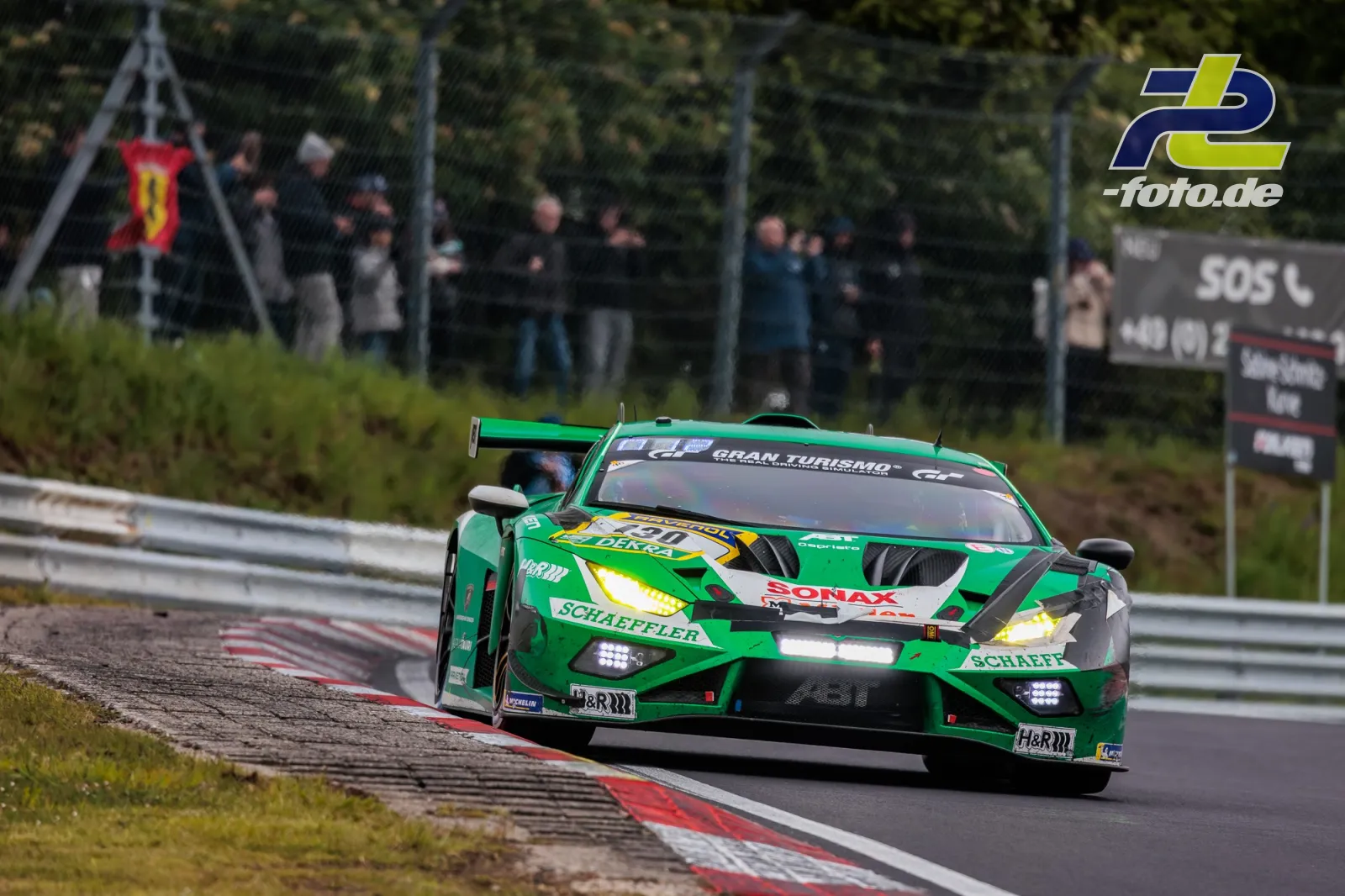 Grüner Lamborghini Huracán GT3 in einer Kurve der Nürburgring-Nordschleife, Zuschauer im Hintergrund, 24h-Rennen 2026.