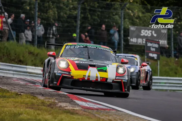 Porsche GT3-Rennwagen in bunter Lackierung auf der Nordschleife beim 24h-Rennen Nürburgring, gefolgt von zwei weiteren Fahrzeugen