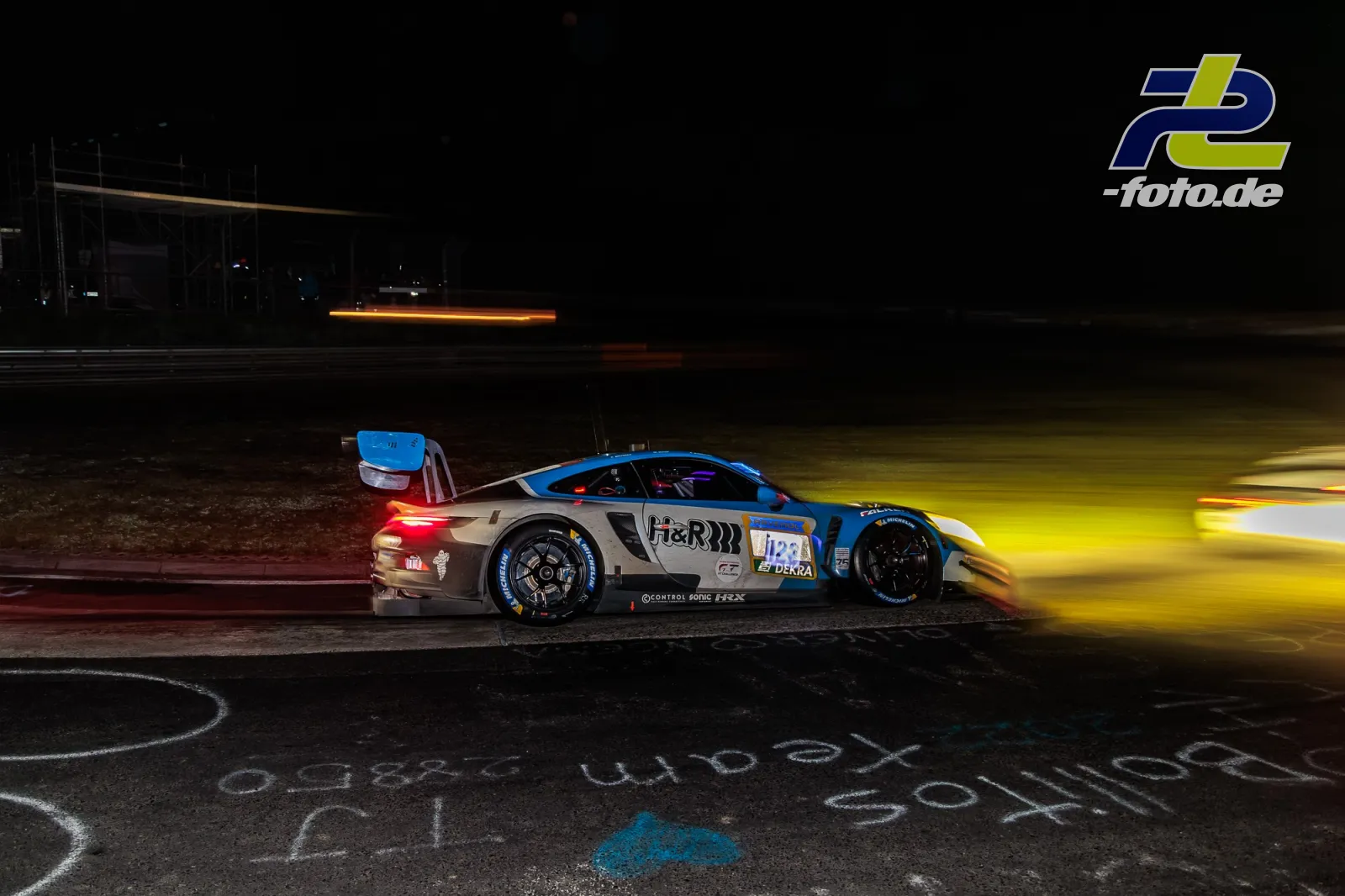 Porsche 911 GT3 R #123 bei Nacht auf der Nordschleife beim 24h-Rennen Nürburgring, beleuchtet von gelbem Scheinwerferlicht.