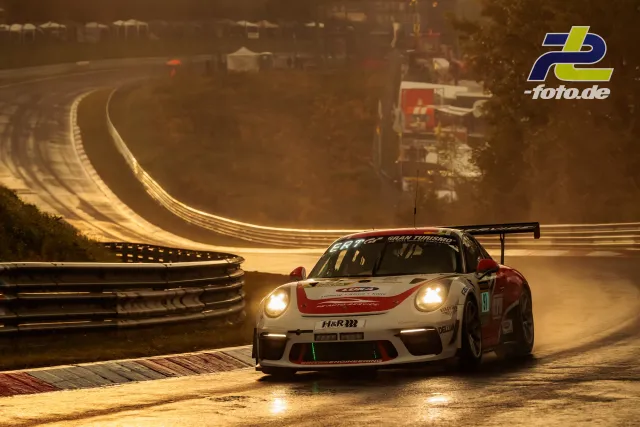 Porsche 911 GT3 Cup mit Startnummer 91 in der Kurve bei Gegenlicht auf nassem Asphalt während des 24h-Rennens auf dem Nürburgring.