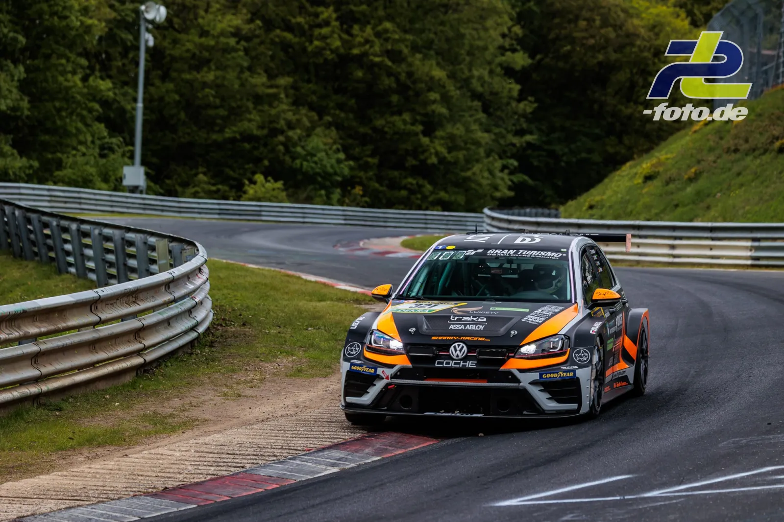 VW Golf 7 GTI TCR DSG in orange-schwarzer Lackierung fährt durch eine Kurve auf der Nürburgring-Nordschleife beim 24h-Rennen.